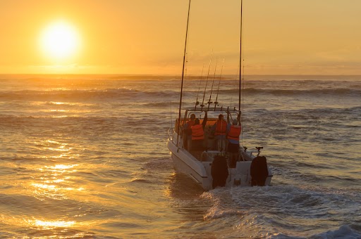 Fishing boat launching at sunrise with fishing rods and outboard motors.